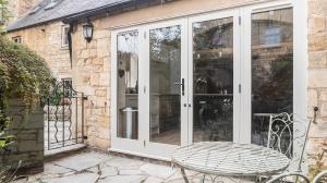 a white sliding glass door with a bench in front at Grooms Lodge, Chipping Campden - Taswell Retreats in Chipping Campden