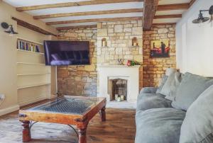 a living room with a couch and a fireplace at Grooms Lodge, Chipping Campden - Taswell Retreats in Chipping Campden