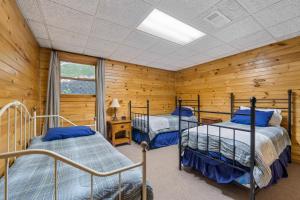 two beds in a room with wooden walls at Nana's Nest in Blue Ridge