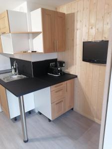 a small kitchen with a black counter and a sink at Appartement plein sud, Val Thorens Centre in Val Thorens