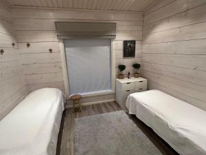 two beds in a room with wooden walls and a window at Villa Paadar in Inari
