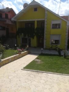 una casa amarilla con una entrada delante de ella en Apartman Zivic, en Berilovac