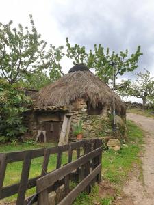 une petite cabane au toit de chaume à côté d'une clôture dans l'établissement Casas Rurales El Cerro y El Cerezo, à Navaconcejo