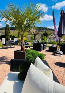 a patio with a table and chairs and a palm tree at Maxhof Trier in Trier +107 photos