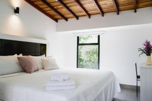 Un dormitorio con una cama blanca con toallas. en Hotel Casa Luna en Cúcuta