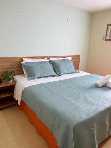 a bedroom with a large bed with blue pillows at Imperial Suítes by Prado in Petrópolis