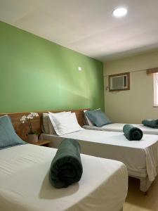 a room with three beds with green walls at Imperial Suítes by Prado in Petrópolis