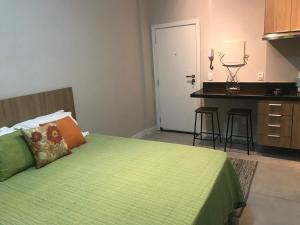 1 dormitorio con 1 cama verde y cocina en Fantástico STUDIO DIVISA COPACABANA IPANEMA REFORMADO E DECORADO, en Río de Janeiro