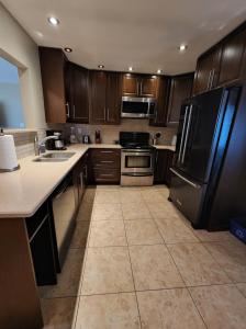 uma cozinha com armários de madeira e um frigorífico preto em Feel at home, Country style family house. em Magrath