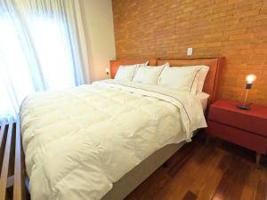 格拉馬杜的住宿－Austin Suites Gramado，卧室配有一张白色大床和砖墙