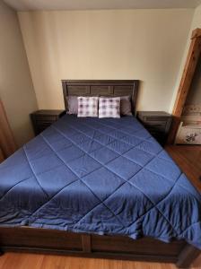a bed with a blue comforter and two pillows at Feel at home, Country style family house. in Magrath