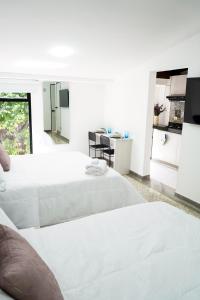 a white bedroom with two beds and a kitchen at Hotel Casa Luna in Cúcuta