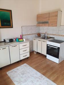 uma cozinha com armários brancos e um forno com placa de fogão em Kuca za odmor i familiju em Bar