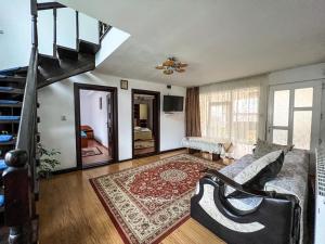 een woonkamer met een trap en een bank bij Casa de langa rau RUCAR in Rucăr