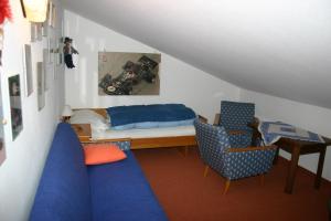 ライト・イム・ヴィンクルにあるGästehaus Obertannerのリビングルーム(青いソファ、ベッド、椅子付)