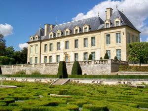 un grand bâtiment avec un jardin en face dans l'établissement Au Bord de l'Oise, à Auvers-sur-Oise