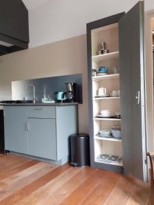 - une cuisine avec un évier et une étagère avec de la vaisselle dans l'établissement Gastenverblijf By ús thús, à Anjum