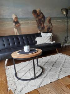 a living room with a black couch and a table at Gastenverblijf By ús thús in Anjum