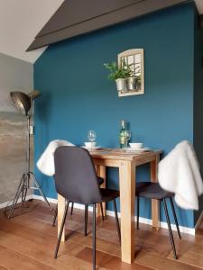uma mesa e cadeiras num quarto com uma parede azul em Gastenverblijf By ús thús em Anjum
