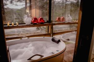 una bañera en una habitación con ventana en Refúgio do Caracol Pipas e Chalés, en Canela