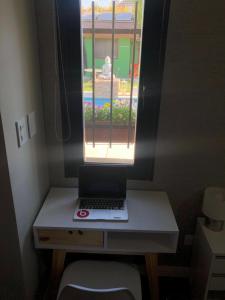 a laptop sitting on a desk under a window at Like at Home Ezeiza in Ezeiza