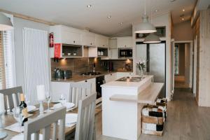 a kitchen and dining room with white cabinets and a table at Casa Di Lusso Luxury lodge in Woodhall Spa
