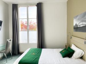 1 dormitorio con cama, ventana y silla en Colette Hôtel en Niort