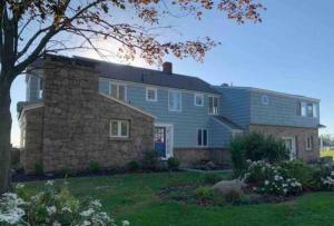 a large stone house with a stone wall at Direct Waterfront 4 Bedroom Beach House With Stunning LI Sound Views & Private Beach in Guilford