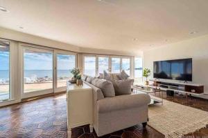 a living room with a couch and a flat screen tv at Direct Waterfront 4 Bedroom Beach House With Stunning LI Sound Views & Private Beach in Guilford