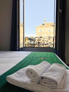 Cette chambre comprend un lit avec des serviettes et une fenêtre. dans l'établissement Colette Hôtel, à Niort