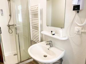 uma casa de banho branca com um lavatório e um chuveiro em Colette Hôtel em Niort