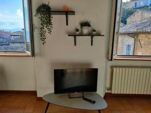 a flat screen tv sitting on a table in a room with two windows at Il cielo di Raffaello in Urbino