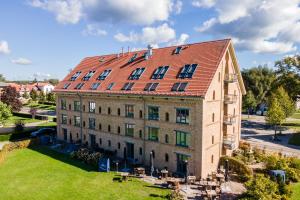 an old building with a red roof on a green field at Hotel Alter Kornspeicher in Neustrelitz