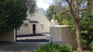 a white house with a tree in front of it at Mountain View Self-Catering Apartment in Somerset West