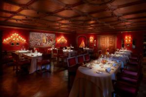 un restaurant avec des tables et des chaises blanches et des murs rouges dans l'établissement Hotel Miramonti, à Cogne