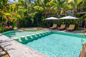 a pool with chairs and umbrellas in a resort at Muúnek Hotel Boutique Art & Spa, adults only in Barra Vieja
