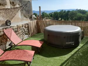 bañera de hidromasaje y 2 sillas en un patio en Un balcon entre Causses et Rougiers, en Gissac