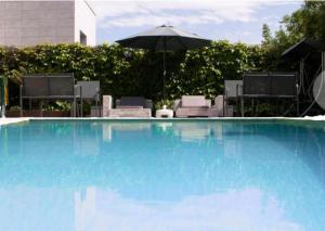 a large blue swimming pool with an umbrella and chairs at Villa Playa San Juan in Soto de la Marina