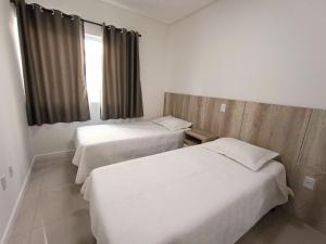 Habitación de hotel con 2 camas y ventana en Residencial Natália, en Bombinhas