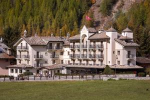 a large white building with a mountain in the background at Hotel Miramonti in Cogne