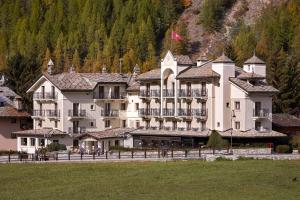 een groot wit gebouw met een berg op de achtergrond bij Hotel Miramonti in Cogne