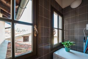 uma casa de banho com uma janela e um WC com uma planta em FEEL - Salvecchio Apartments em Bérgamo