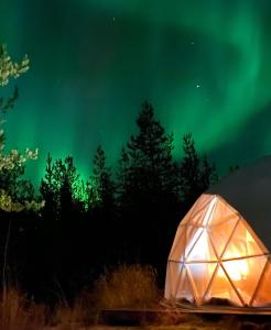a lit up tent under the northern lights at Pandomes Aurora Igloo Hotel in Rovaniemi