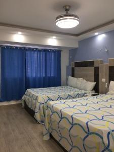 2 Betten in einem Zimmer mit blauen Wänden und blauen Vorhängen in der Unterkunft Hotel Hamilton in Boca Chica