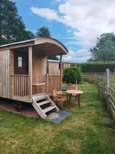 a wooden cabin with a table and a bench at Lucker mill shepherds huts in Lucker