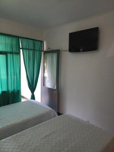 a bedroom with two beds and a television on the wall at Alojamento Central - Funchal in Funchal