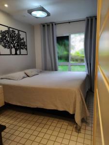 um quarto com uma cama grande e uma janela em Apto Pé na Areia Condomínio Oceanside Camboinhas em Niterói