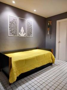 um quarto com uma cama amarela com fotografias na parede em Apto Pé na Areia Condomínio Oceanside Camboinhas em Niterói
