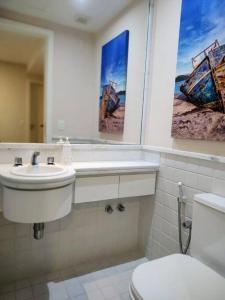 uma casa de banho com um WC, um lavatório e um espelho. em Apto Pé na Areia Condomínio Oceanside Camboinhas em Niterói