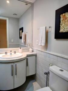 uma casa de banho com um lavatório, um WC e um espelho. em Apto Pé na Areia Condomínio Oceanside Camboinhas em Niterói